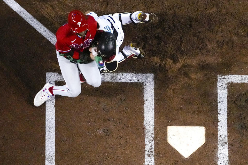 Philadelphia Phillies' Bryce Harper scores past Arizona Diamondbacks catcher Gabriel Moreno after colliding during the first inning in Game 5 of the baseball NL Championship Series in Phoenix, Saturday, Oct. 21, 2023. (AP Photo/Brynn Anderson)