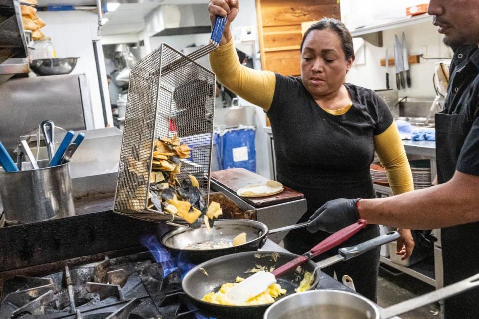 Fabiola Vazquez helps make a chilaquiles with gas equipment at La Cosecha Wednesday.