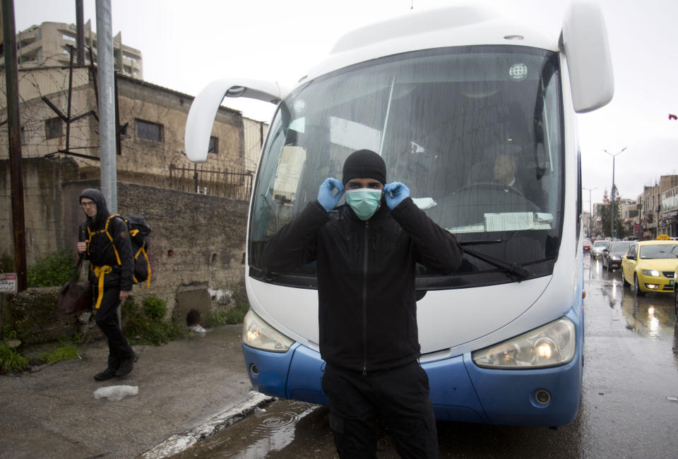 Palestinian policeman stop tourist busses as preventive measures are taken against the coronavirus, in Bethlehem, West Bank, Friday, March 6, 2020. Foreign tourists say they are being denied entry to the biblical West Bank city of Bethlehem a day after Israeli and Palestinian authorities took measures to prevent the spread of the new coronavirus. (AP Photo/Majdi Mohammed)