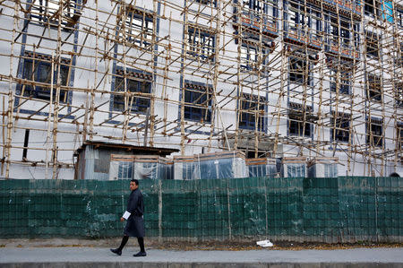 A man walks past a housing construction site in the capital city of Thimphu, Bhutan, December 12, 2017. REUTERS/Cathal McNaughton