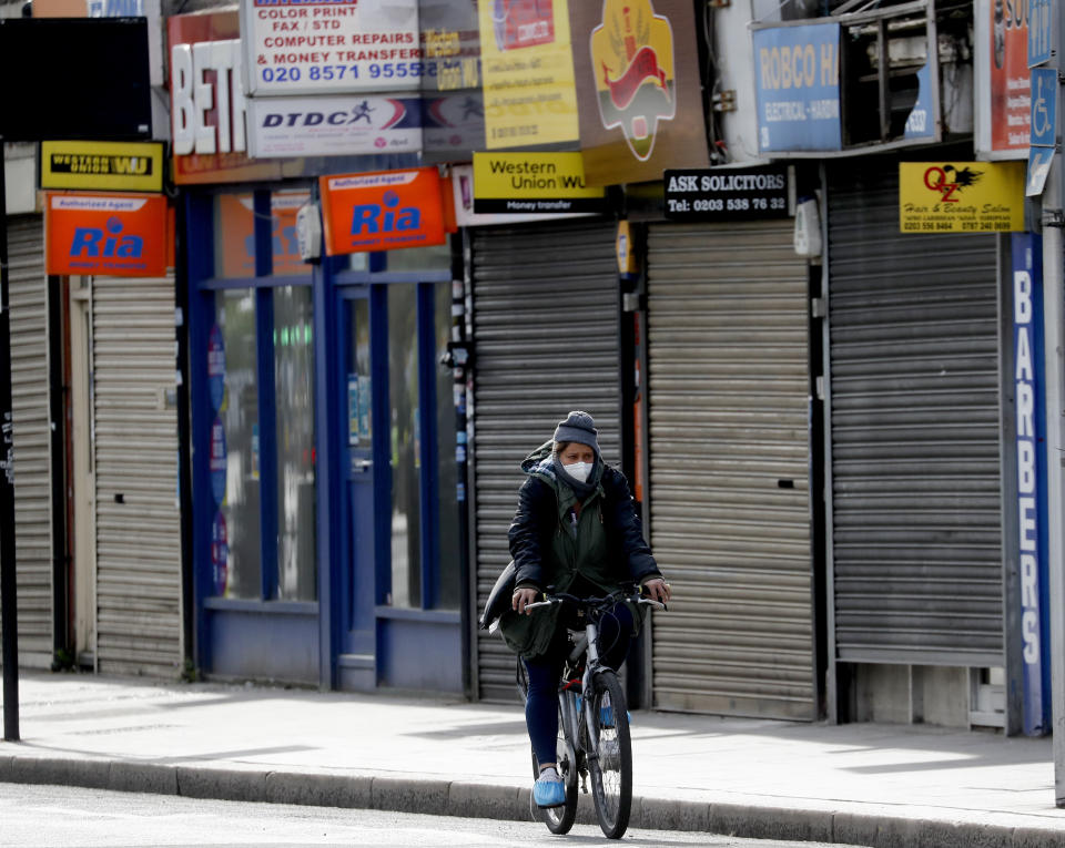 A cyclist rides past shops In London, closed due to the coronavirus lockdown. (Frank Augstein/AP)