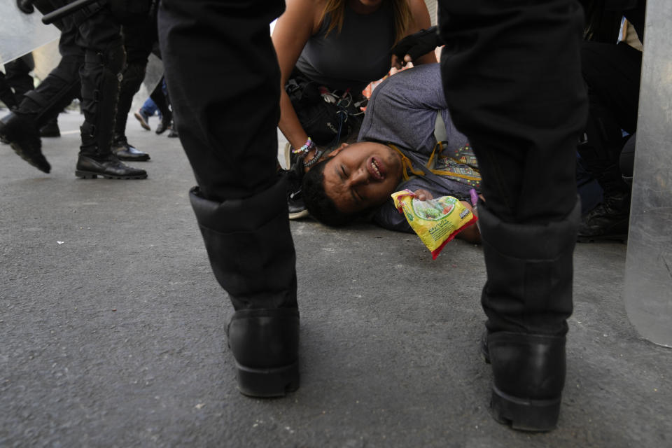 Police stand around protester who was injured during in a march against President Dina Boluarte in Lima, Peru, Thursday, Jan. 19, 2023. Protesters are seeking immediate elections, the resignation of Boluarte, the release from prison of ousted President Pedro Castillo and justice for protesters killed in clashes with police.(AP Photo/Martin Mejia)