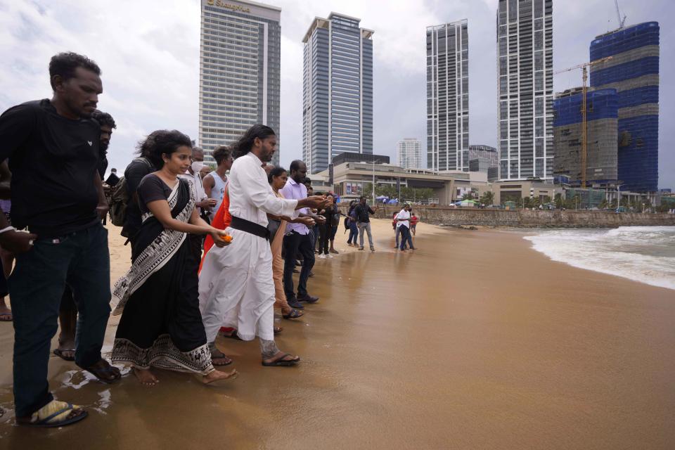 Human rights activists walk to offer flowers to the sea in remembrance of victims of Sri Lanka's civil war, at the ongoing anti government protest site in Colombo, Sri Lanka, Wednesday, May 18, 2022. Sri Lankan protesters lit flames and offered followers on Wednesday remembering thousands including ethnic Tamil civilians killed in the final stages of the country's long civil war, in the first-ever event where mostly majority ethnic Sinhalese openly memorialised the minority group. (AP Photo/Eranga Jayawardena)