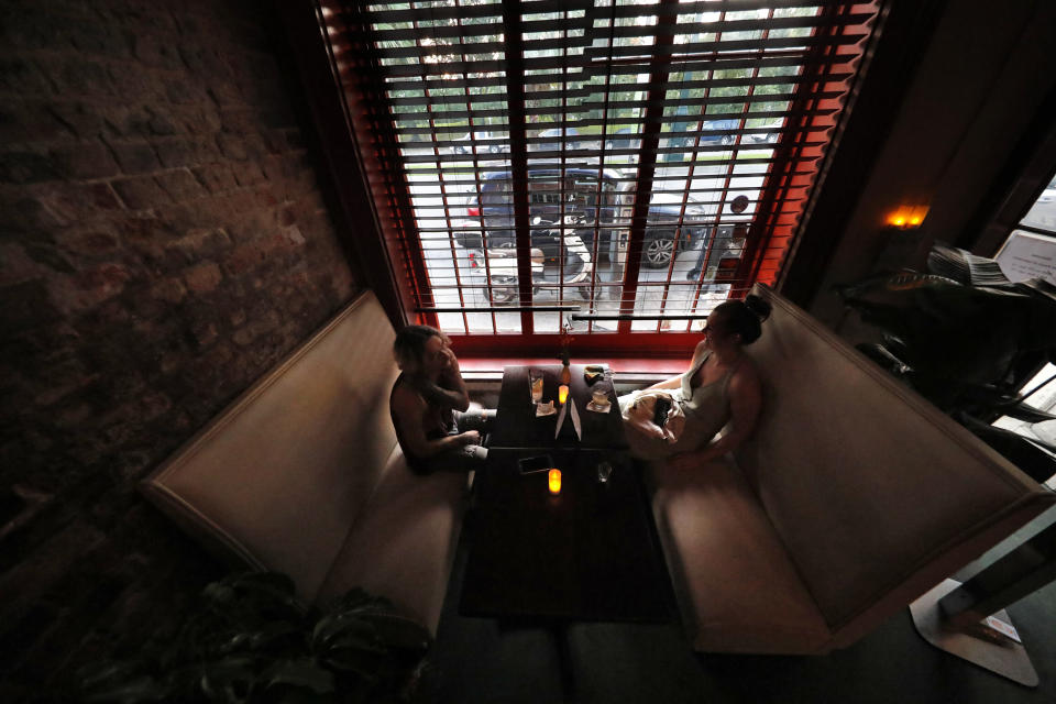 Patrons sit in a booth inside Bar Tonique in New Orleans, Thursday, July 9, 2020. A sharp increase in COVID-19 cases and hospitalizations is forcing bars in the good-time-loving, tourist-dependent city to shut down again just a month after they were allowed to partially reopen. (AP Photo/Gerald Herbert)