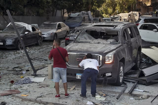 A man inspects his a damaged car after a massive explosion in Beirut