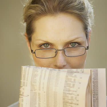 Woman-in-glasses-looking-over-folded-newspaper_web