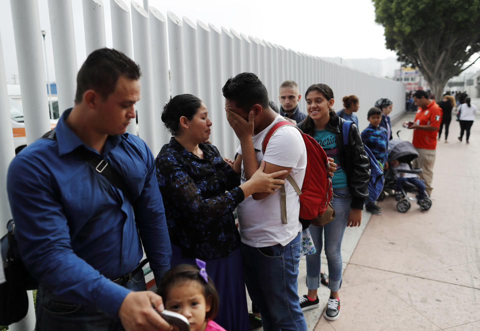 Calet Garcia, center, of Honduras, cries once he realizes he will be able to apply for asylum in the U.S. with his friend Daisy Avelar, second from left, of El Salvador, Thursday, July 26, 2018, near the San Ysidro port of entry in Tijuana, Mexico. As the Trump administration faced a court-imposed deadline Thursday to reunite thousands of children and parents who were forcibly separated at the U.S.-Mexico border, asylum seekers continue to arrive to cities like Tijuana, hoping to plead their cases with U.S. authorities. (AP Photo/Gregory Bull)