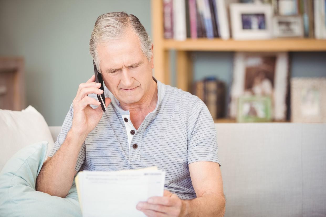 senior man on the phone holding papers