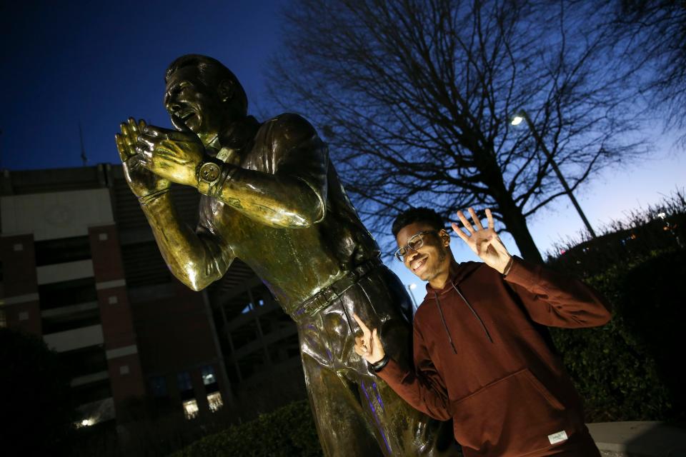 Jan 10, 2024; Tuscaloosa, Alabama, USA; Nathan Reed, a University of Alabama student from Montgomery, holds up six fingers, representing the six national championships won by retiring Alabama head football coach Nick Saban as he poses for a photo beside the statue of Saban on the Walk of Champions outside Bryant-Denny Stadium. Mandatory Credit: Gary Cosby Jr.-USA TODAY Sports