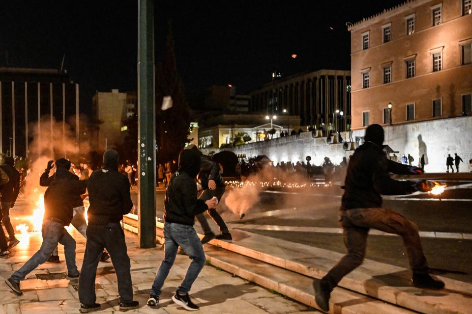 Youths throw molotov coktails in front of the Greek parliament in Athens on March 3, 2023, as parallel demonstrations take place, following the deadly accident near the city of Larissa, where 57 people, mainly students lost their lives. - Thousands of Greek students staged sit-ins and demonstrated in Athens and other cities on March 3 to demand justice for the victims of the train tragedy, which occured on February 28, as authorities admitted failures overseeing the rail network. In Athens, over 5,000 people gathered outside the headquarters of Greek rail operator Hellenic Train to voice anger and sorrow over the country's worst-ever rail disaster. (Photo by Louisa GOULIAMAKI / AFP) (Photo by LOUISA GOULIAMAKI/AFP via Getty Images)