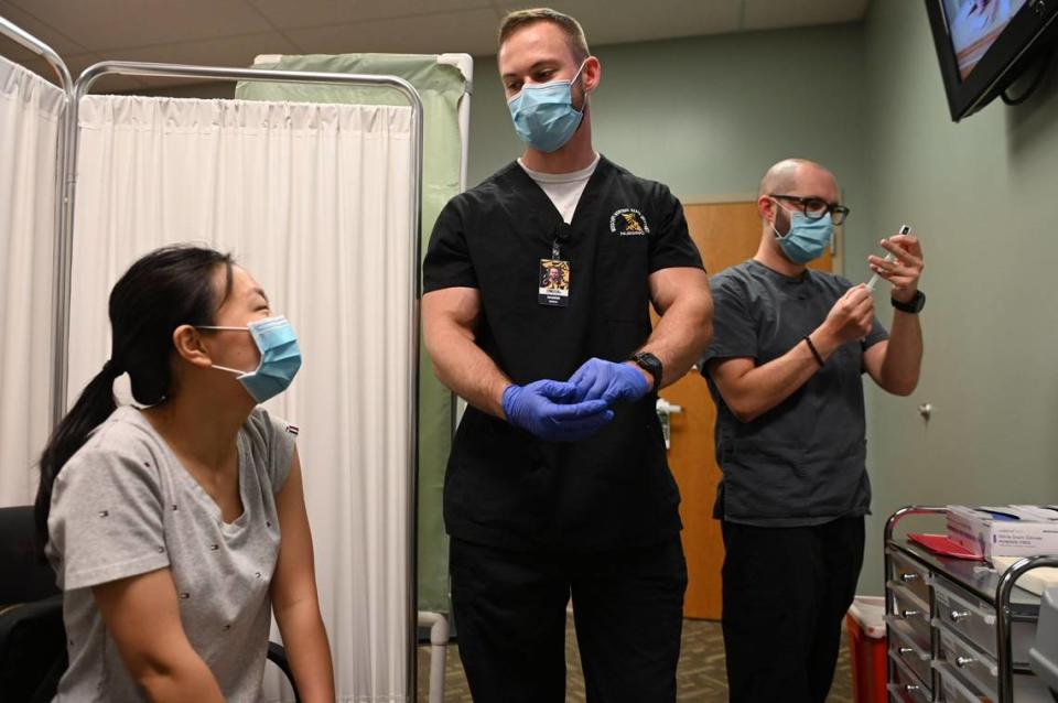 Kangyuan Zhao of Platte County, Missouri, talked with Jeremiah Smith, a nursing student at Missouri Western State University, as Dustin Guest, immunization coordinator, prepared the Pfizer COVID-19 vaccination on Thursday at the Parkville clinic of the Platte County Health Department. Earlier this year, Zhao was infected with COVID-19.