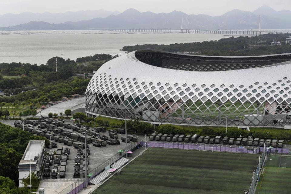 This Friday, Aug. 16, 2019, photo shows armored vehicles and troop trucks are parked outside Shenzhen Bay Stadium in Shenzhen, China. Members of China's paramilitary People's Armed Police marched and practiced crowd control tactics at a sports complex in Shenzhen across from Hong Kong on Friday, in what some interpreted as a threat against pro-democracy protesters in the semiautonomous territory.(Madoka Ikegami/Kyodo News via AP)