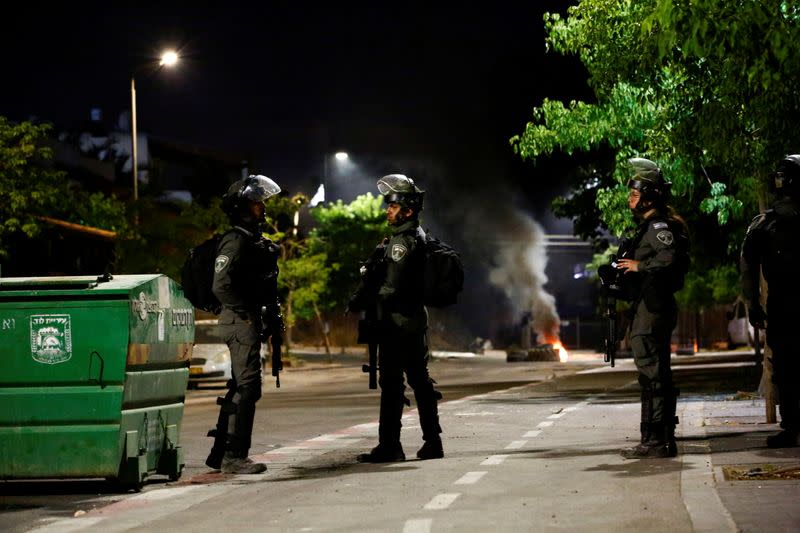 FILE PHOTO: Israeli Border Police force members stand near burning tires by one of the entrances to the Arab-Jewish town of Lod