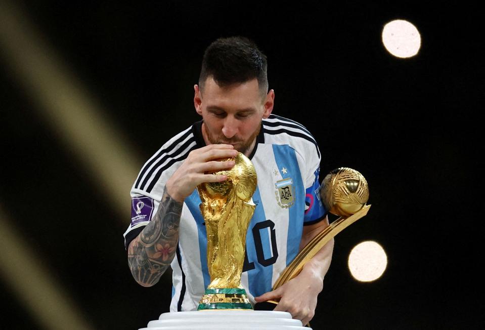 阿根廷奪下世界盃冠軍，梅西上台先領金球獎時忍不住偷親大力神盃。（路透社）