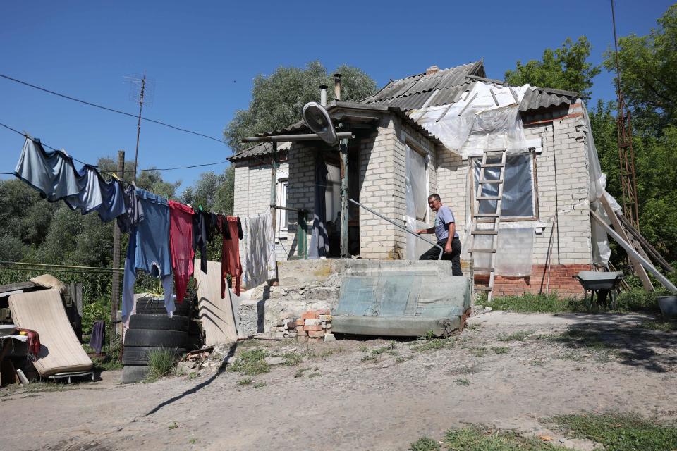 Local resident Oleksandr Prokopovich, 58, works outside his damaged house in Mala Komyshuvakha village, Kharkiv, 8 August (AFP via Getty Images)