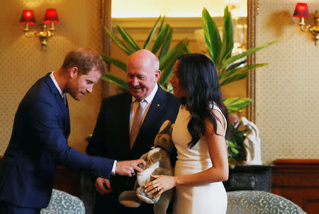 Britain's Prince Harry reacts to a plush kangaroo held by wife Meghan, Duchess of Sussex next to Australia's Governor General Peter Cosgrove at Admiralty House during their visit in Sydney, Australia October 16, 2018. REUTERS/Phil Noble/Pool