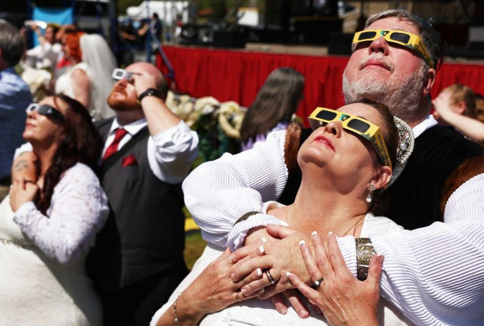 Couples view the solar eclipse during a mass wedding at the Total Eclipse of the Heart festival on April 8, 2024 in Russellville, Arkansas.