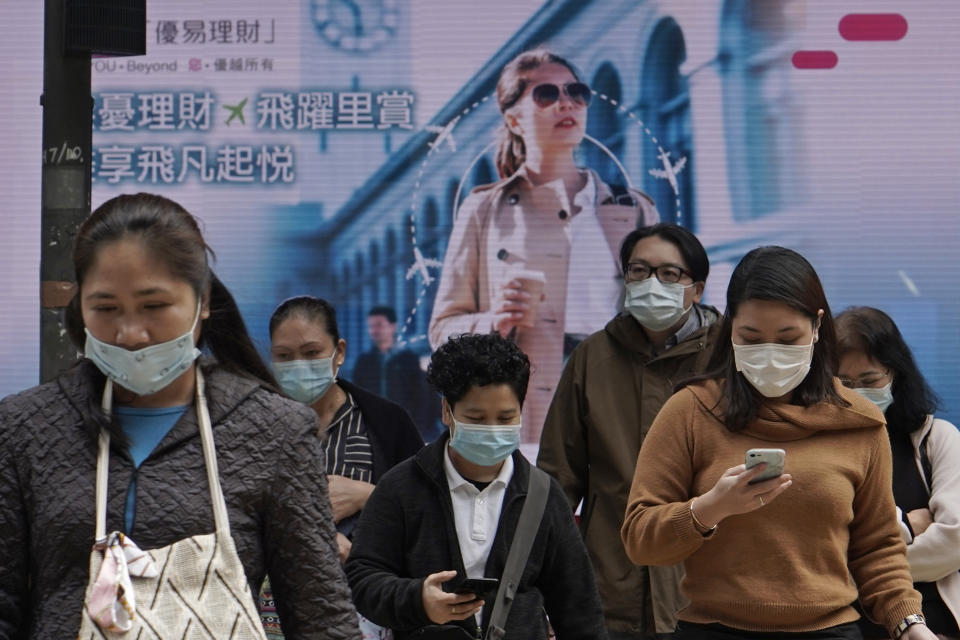 People wearing protective face masks walk on a street in the Central, the business district of Hong Kong, Tuesday, Feb. 11, 2020. China's daily death toll from new virus has topped 100 for first time, with more than 1,000 total deaths recorded, the health ministry announced Tuesday, as the spread of the contagion shows little sign of abating while exacting an ever-rising cost. (AP Photo/Kin Cheung)