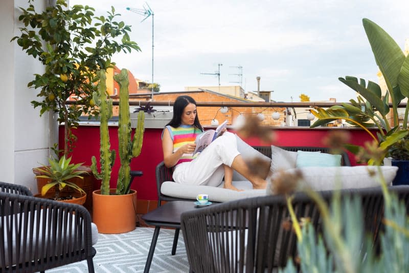 A dweller reads in an outdoor space surrounded by plants