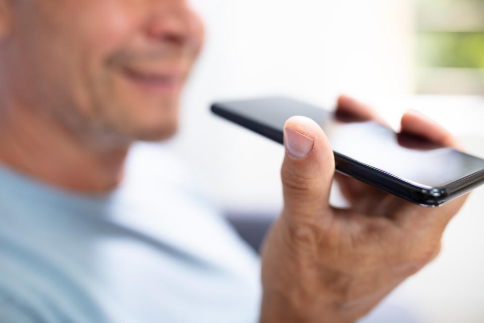 Close-up Of A Beard Man Using Voice Recognition Function On Mobile Phone Against White Background