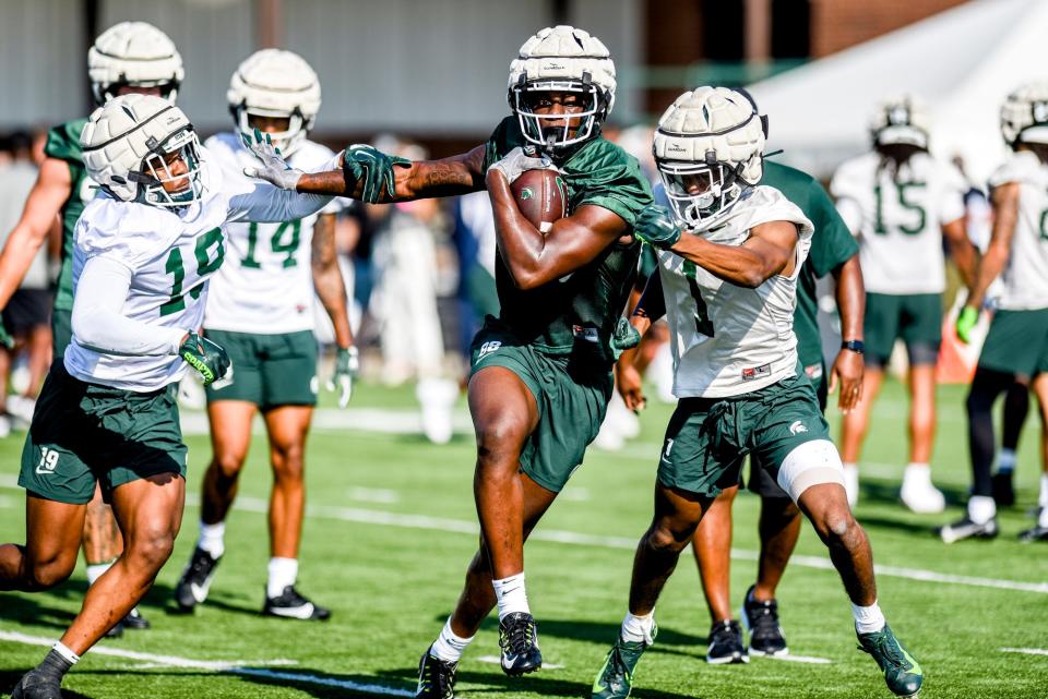 Michigan State tight end Ademola Faleye, center, runs with the ball as defensive backs Armorion Smith, left, and Jaden Mangham close in during the opening day of MSU's football fall camp on Thursday, Aug. 3, 2023, in East Lansing. Faleye (Norfolk State) and Smith (Cincinnati) are two of the Spartans' 18 transfer additions this season.