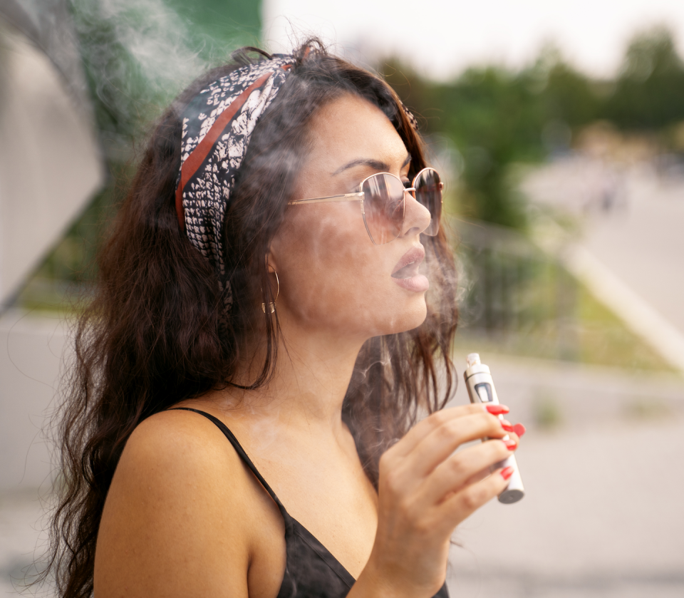 a person with a bandana and glasses holding a bottle of soda