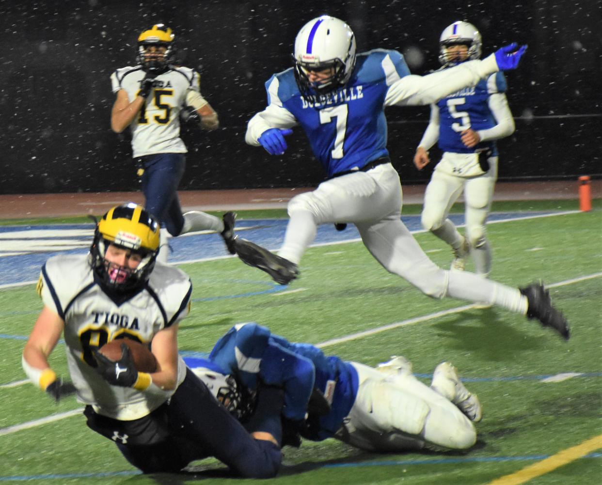 Dolgeville Blue Devil Connor Kraszewski (7) leaps over teammate Isaiah Rathbun's tackle of Tioga Tiger Karson Sindoni during the 2022 Class D regional playoff game at Michael J. Bragman Stadium. Dolgville and defending champion Tioga meet in the state playoffs for the third year in a row Friday.