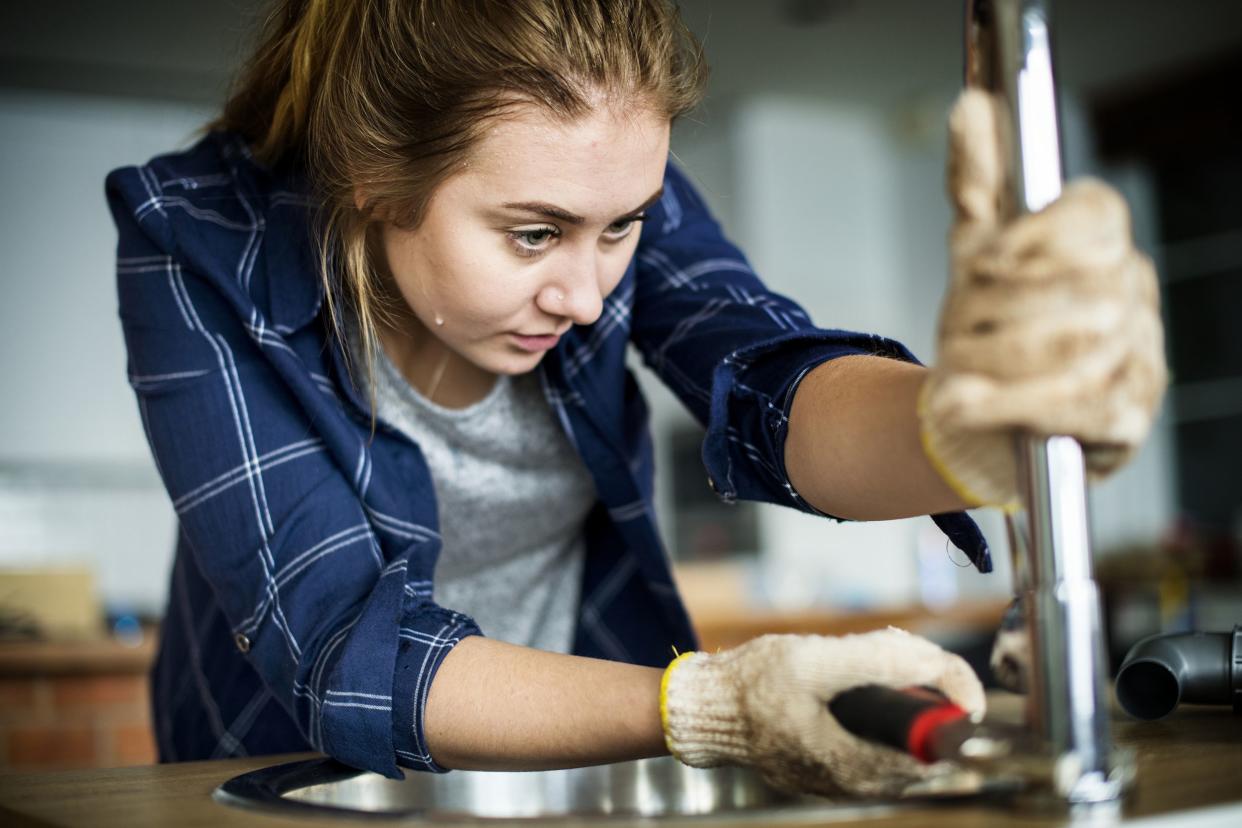 woman fixing kitchen sink