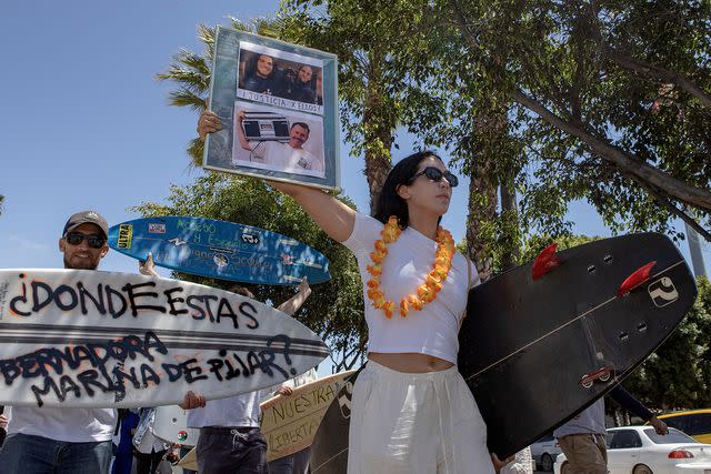 <p>AP Photo/Karen Castaneda</p> A demonstrator holds photos of the foreign surfers who disappeared during a protest in Ensenada, Mexico