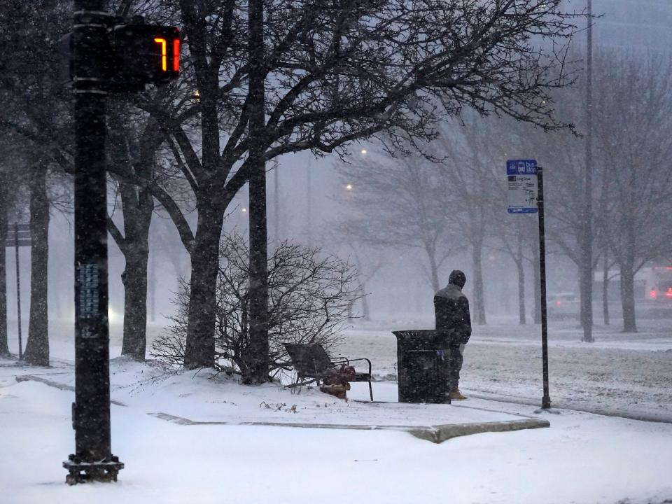 A transit rider waits for a bus as a winter storm descends upon Chicago, Thursday, Feb. 17, 2022.