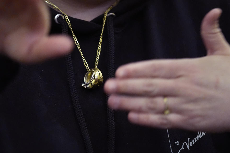 While wearing her and her husband's wedding bands on a necklace, Megan Vozzella, who is deaf, signs while describing future concerns following a visit by Steven Dettelbach, the Director of the Bureau of Alcohol, Tobacco and Firearms, with community members that were personally effected by the October 2023 mass shootings in Lewiston, Maine at Central Maine Community College, Thursday, Feb. 22, 2024, in Auburn, Maine. Vozzella lost her husband Steve, who was also deaf, in the shooting. Four of the 18 victims of the Maine shootings were deaf. (AP Photo/Charles Krupa)