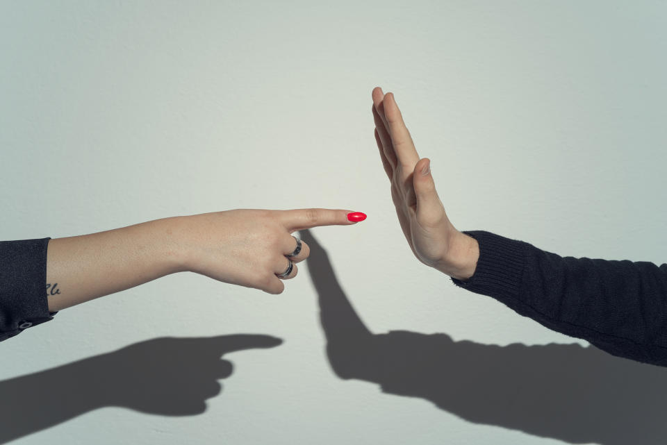 Two hands gesture, one pointing and the other with palm facing out, casting a heart shadow