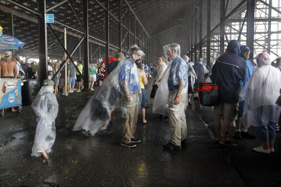 Fans stand under the grandstand after the start of the NASCAR Sprint Cup Series auto race was postponed due to rain on Sunday, Aug. 5, 2012, at Pocono Raceway in Long Pond, Pa. (AP Photo/Mel Evans)