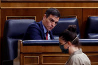 Spain's Prime Minister, Pedro Sanchez looks at far-right Vox party's deputy Macarena Olona wearing a mask to protect against coronavirus, during the opening of a parliamentary session in Madrid, Spain, Thursday, April 9, 2020. Sanchez acknowledged that Spain's government, and its regions which administer health services, were caught off guard by the crisis and left its hospitals woefully short on critical supplies, including virus tests and protective clothing for medical workers. (Mariscal, Pool Photo via AP)