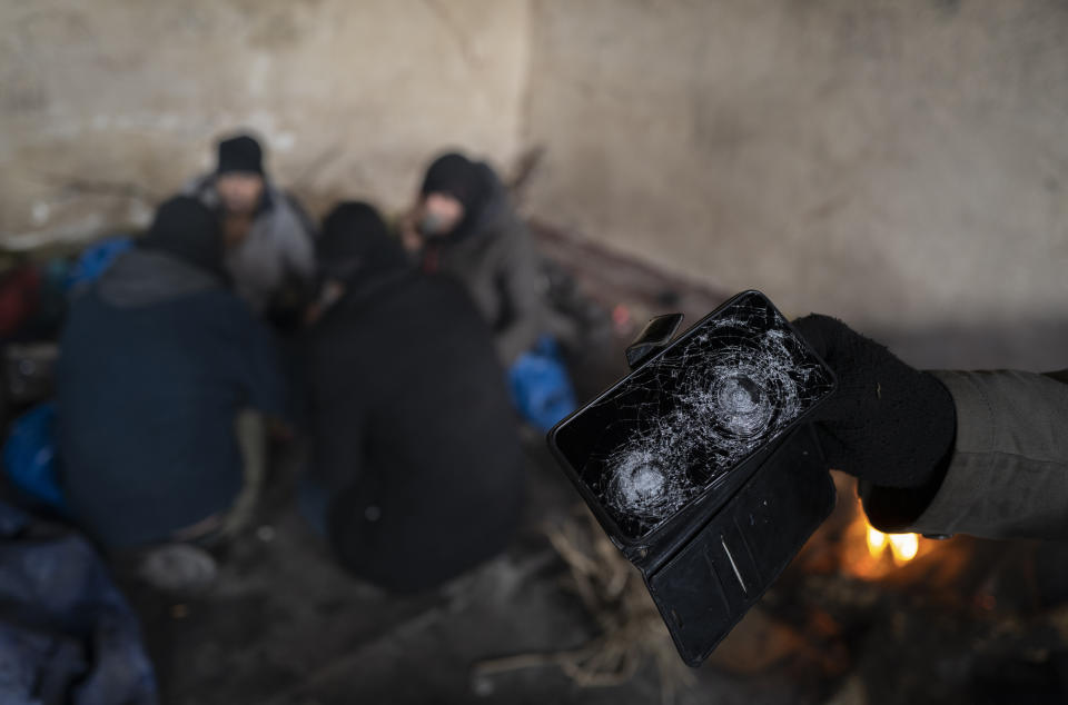 A migrant shows a damaged cellphone, allegedly broken by Romanian police during an unsuccessful border crossing attempt outside of the village of Majdan, Serbia, Tuesday, Jan. 11, 2022. Hungary's nationalist prime minister, Viktor Orban, is keen to use the threat of migrants at his country's southern border to give him an advantage in upcoming elections. But the scale of migration pressure claimed by Orban is drawn into question by statistics from neighboring Serbia and the European Union's border agency. (AP Photo/Bela Szandelszky)