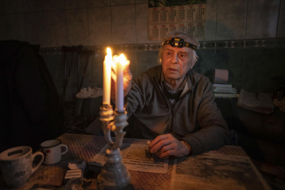 Volodymyr Dubrovsliy, a disabled pensioner, lights candles in his house after living without electricity for more than four months in Kupiansk, Kharkiv region, Ukraine, Wednesday, Dec. 28, 2022. (AP Photo/Evgeniy Maloletka)