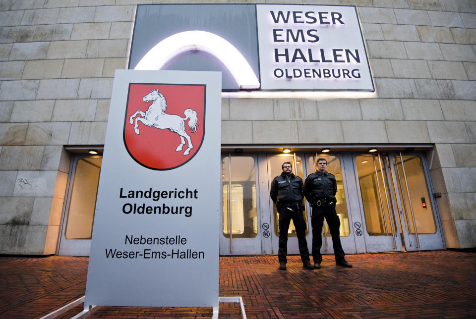 Police officers stay in front of the temporay Oldenburg district court at the Weser Ems halls in Oldenburg, Germany, Tuesday, Oct. 30, 2018. A nurse serving a life sentence for two murders is going on trial on charges that he killed a further 100 patients at two hospitals in Germany. (Julian Stratenschulte/dpa via AP)