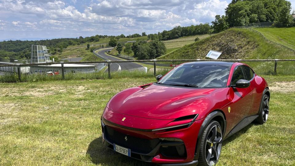 a red ferrari purosangue parked on grass