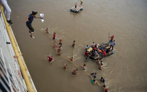 Migrants tired of waiting to cross into Mexico, jumped from a border bridge into the Suchiate River - Credit: Oliver de Ros/AP