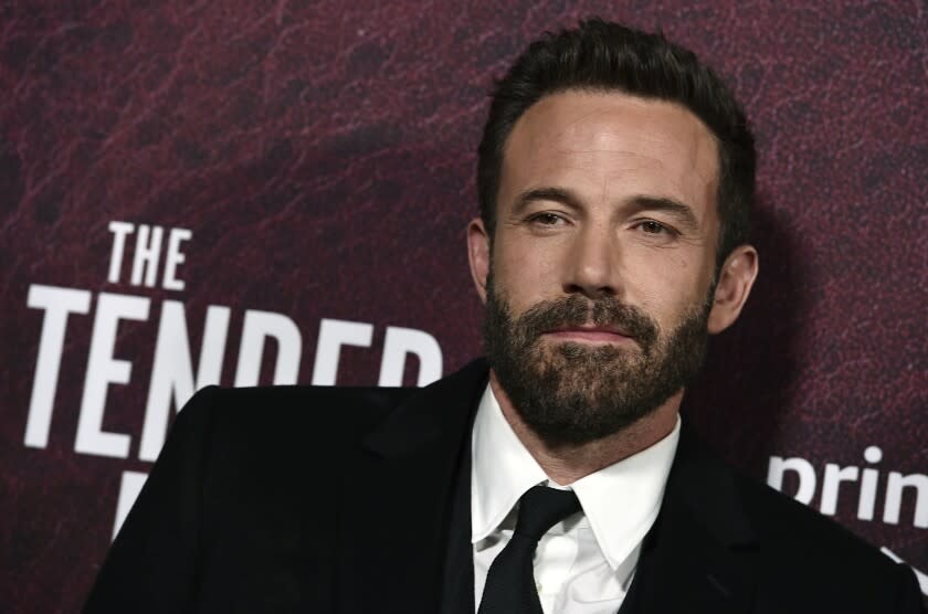 A man with brown hair and a goatee poses for pictures at a red carpet event.