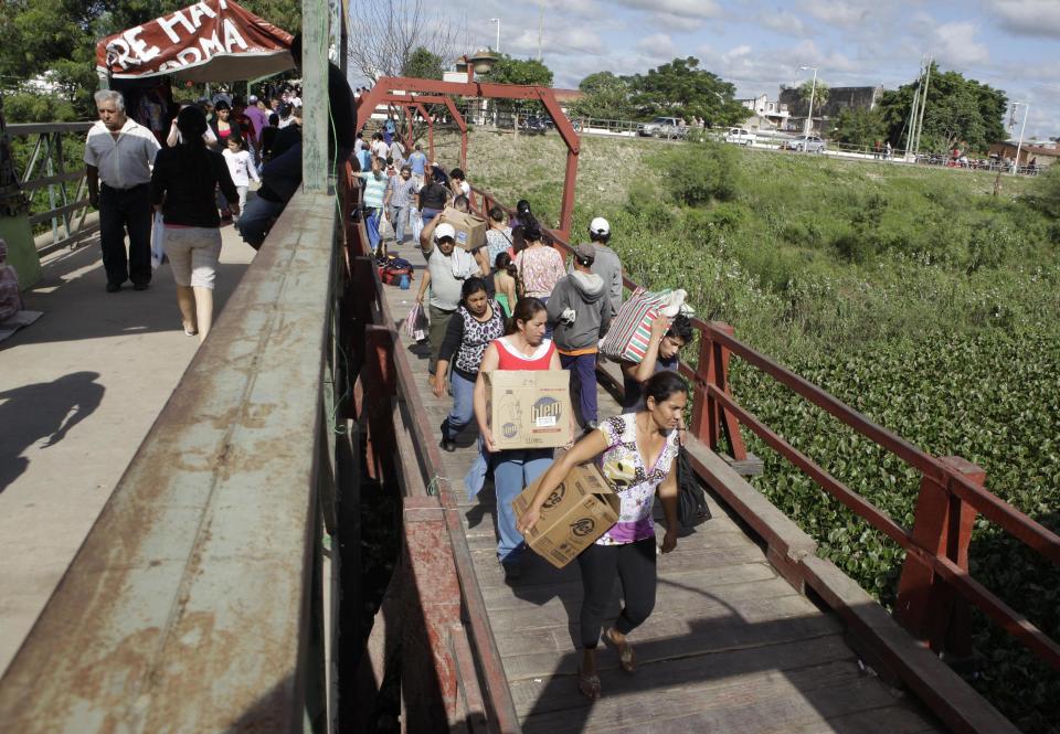 In this June 1, 2013 photo, Paraguayans return from shopping in Clorinda, Argentina as they cross an international bridge over the Pilcomayo River into the town of Nanawa, Paraguay. Shoppers who turn to the street rather than the banks to swap their dollars are getting a bonanza of extra Argentine pesos and can shop much more cheaply than back at home due to Argentina's currency controls and black market for US dollars. Taking advantage of the guarani’s newfound strength, Paraguayans are rolling by the thousands into the Argentine frontier city of Clorinda to do their shopping. (AP Photo/Jorge Saenz)