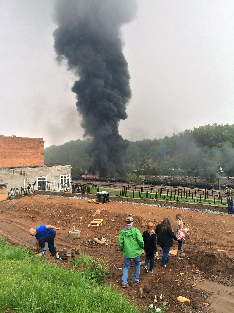 In this mobile phone photo provided Charles Peters, smoke rises after several CSX tanker cars carrying crude oil derailed on Wednesday, April 30, 2014, in Lynchburg, Va. Authorities evacuated numerous buildings Wednesday after the derailment. (AP Photo/Charles Peters) MANDATORY CREDIT