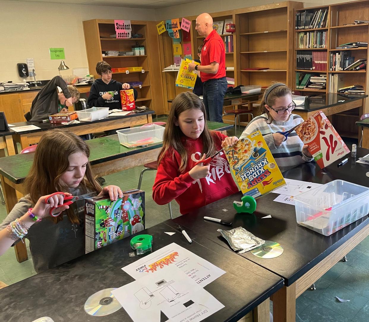 From left, Utica Middle School sixth graders Joslyn Snyder, Chloe Meek and Cloey Schwenke build their CD spectrometers last week during a STEM project.