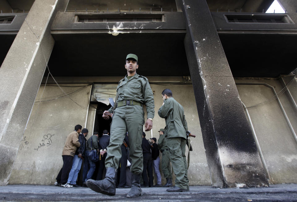 FILE - In this Monday, March 21, 2011 file photo, A Syrian army soldier steps out from the burned court building that was set on fire by Syrian anti-government protesters, in the southern city of Daraa, Syria. It began innocently enough in March 2011, with a short phrase spray-painted on a schoolyard wall by teenagers in the southern Syrian city of Daraa: “Your turn is coming, doctor.” The doctor referred to President Bashar Assad, a trained ophthalmologist, and the implication was that he too would fall from power like his counterparts in Tunisia and Egypt who had recently been toppled in popular revolts. Nearly three years after the crisis began, Syria's government and opposition are set to meet in Geneva this week for the first direct talks aimed at ending the conflict. (AP Photo/Hussein Malla, File)