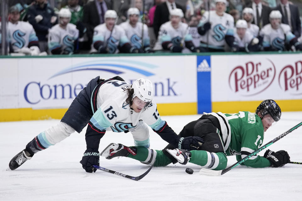 Dallas Stars center Ty Dellandrea (10) is knocked to the ice by Seattle Kraken left wing Brandon Tanev (13) as the two chased the puck during the first period of an NHL hockey game Tuesday, March 21, 2023, in Dallas. (AP Photo/Tony Gutierrez)