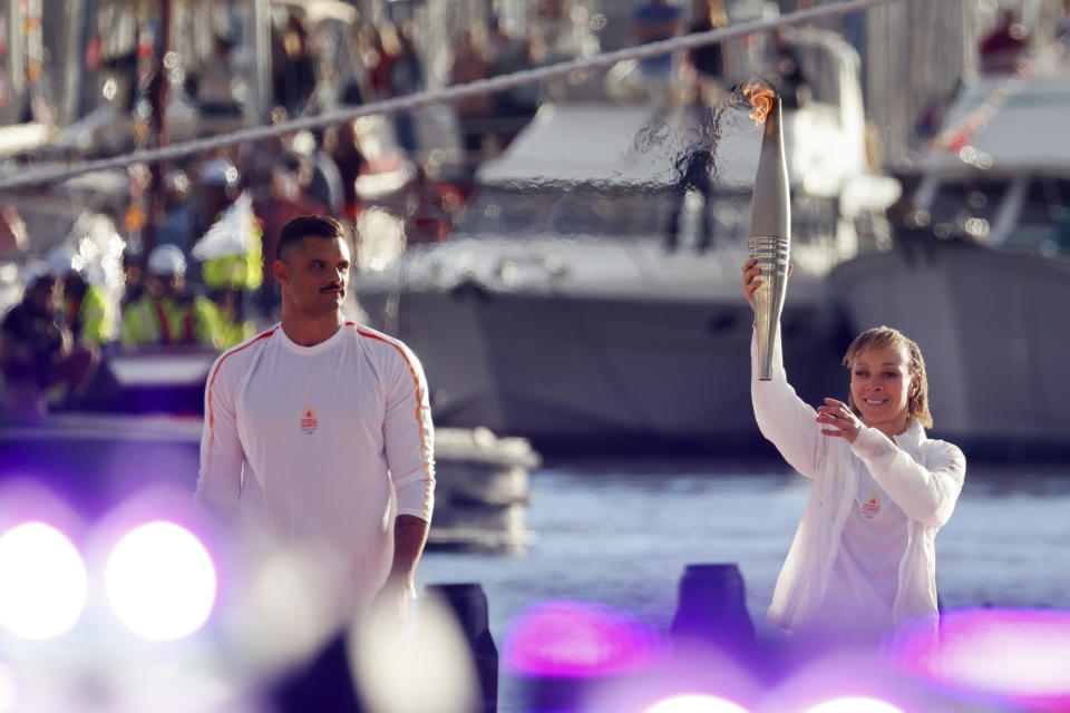 French Paralympic athlete Nantenin Keïta, holds the Olympic torch while French swimmer Florent Manaudou looks on during the torch arrival ceremonyl in Marseille, southern France, Wednesday May 8, 2024. After leaving Marseille, a vast relay route is undertaken before the torch odyssey ends on July 27 in Paris. The Paris 2024 Olympic Games will run from July 26 to Aug.11, 2024. Keita is visually impaired and won a gold medal during the 2016 Olympics in Rio de Janeiro. (Ludovic Marin, Pool via AP)