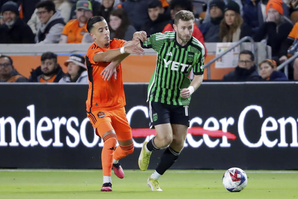 Houston Dynamo midfielder Amine Bassi, left, pulls on Austin FC forward Jon Gallagher, right, as Gallagher moves the ball during the second half of an MLS soccer match Saturday, March 18, 2023, in Houston. (AP Photo/Michael Wyke)