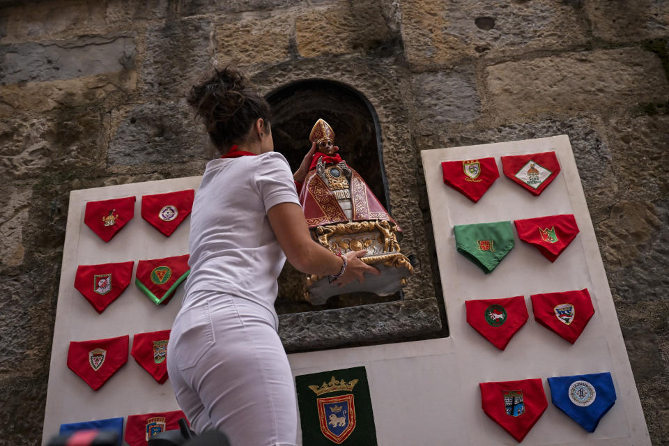 A woman places a figure of Saint Fermín, ahead of the first day of the running of the bulls during the San Fermin fiestas in Pamplona, Spain, Friday, July 7, 2023. (AP Photo/Alvaro Barrientos)