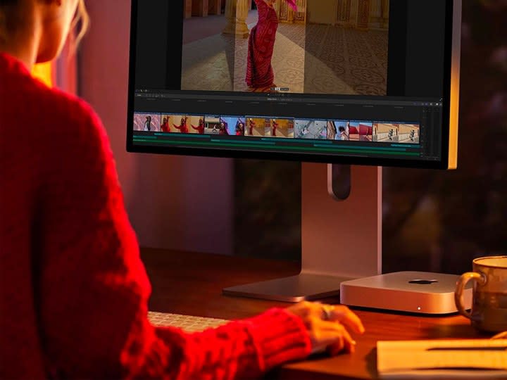 A woman works at her desk on an Apple Mac Mini M2 computer.