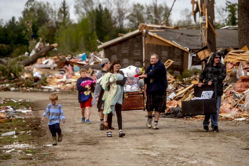 Resident Stephanie Kerwin, center, holds her baby Octavius in one arm and dog Pixie in the other as she and her family carry what they could salvage from her home in Nottingham Forest Mobile Home Park, Saturday, May 21, 2022, in Gaylord, Mich., following a tornado the day before. "This morning is when it first hit me...I could have lost people that I really love. I am so grateful," Kerwin said. (Jake May/MLive.com/The Flint Journal via AP)